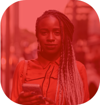 Mulher com uma roupa laranja segurando um celular e com um sorriso de canto e ao fundo prédios.