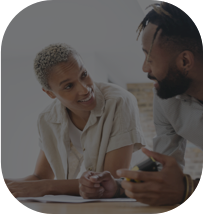 Casal conversando, olhando um para o outro e sorrindo enquanto estão apoiados em uma mesa.